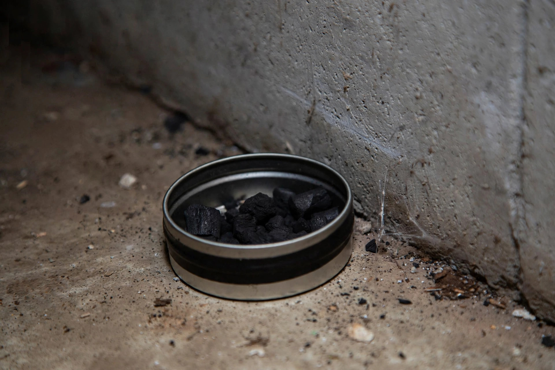Close-up of a charcoal radon test canister kit on a basement floor next to a wall, indoor